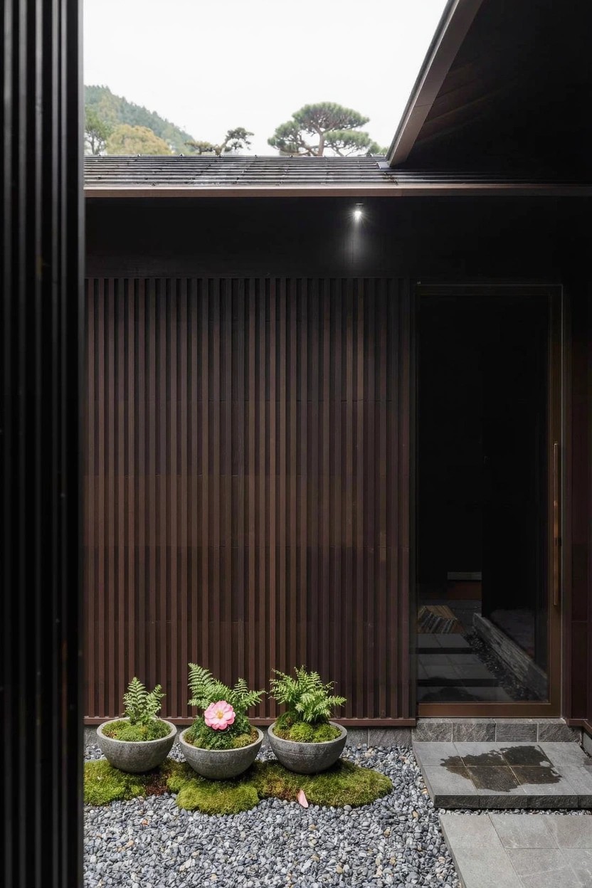 White stucco wall with black-framed windows and entry door, window boxes overflowing with red and orange poppy flowers on the sills.