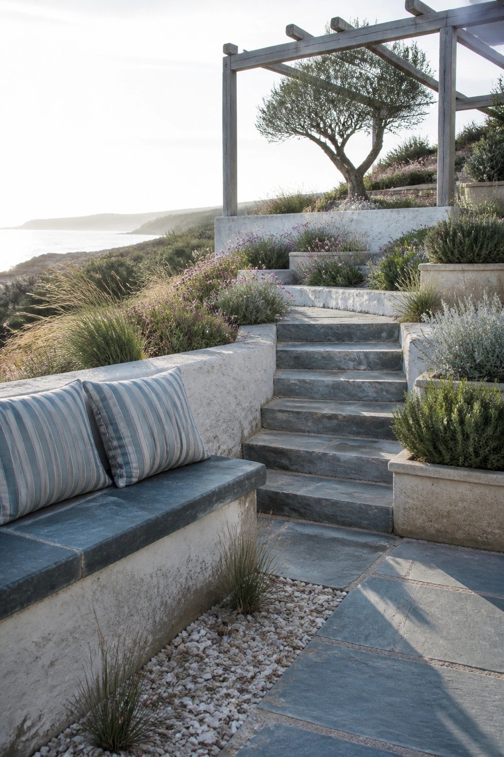 Stone steps and bench with striped cushions in coastal garden at sunset
