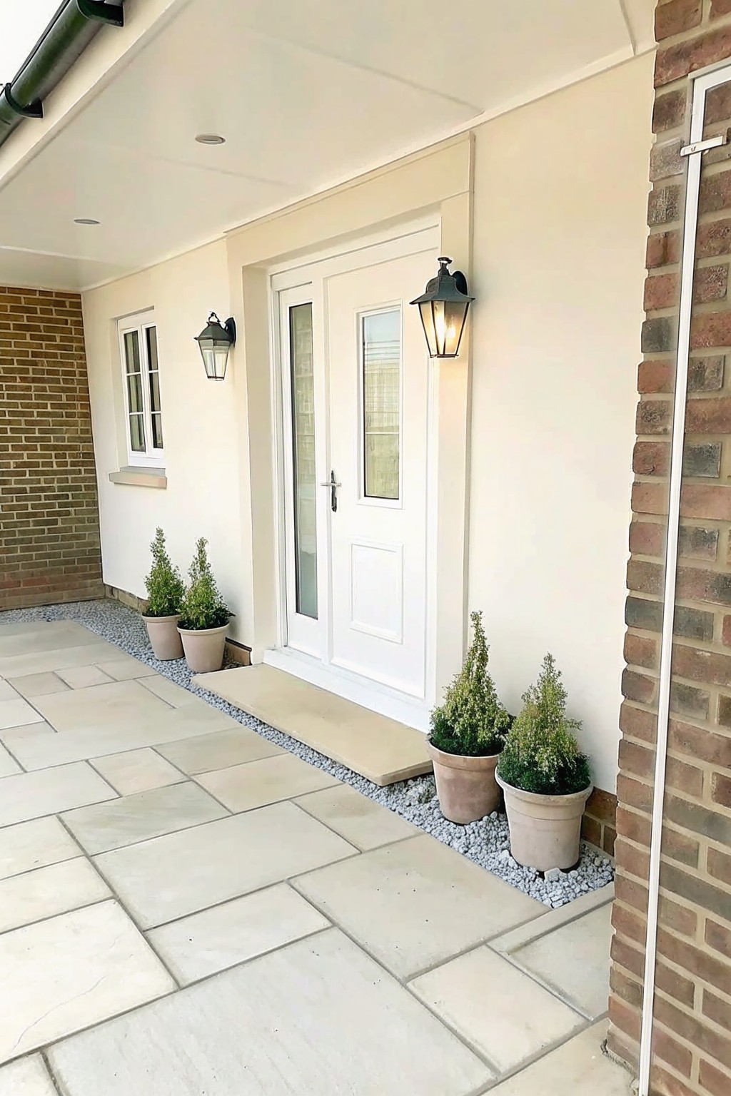 White double doors with potted plants, lanterns, and stone patio entrance