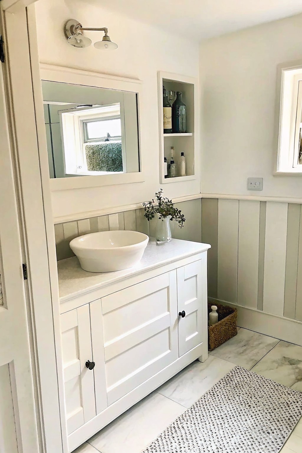 White bathroom vanity with vessel sink, marble countertop, mirror, and wainscoted walls