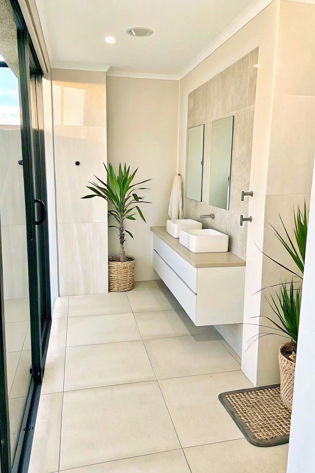 Modern minimalist bathroom with floating white vanity, two sinks, mirrors and potted plants