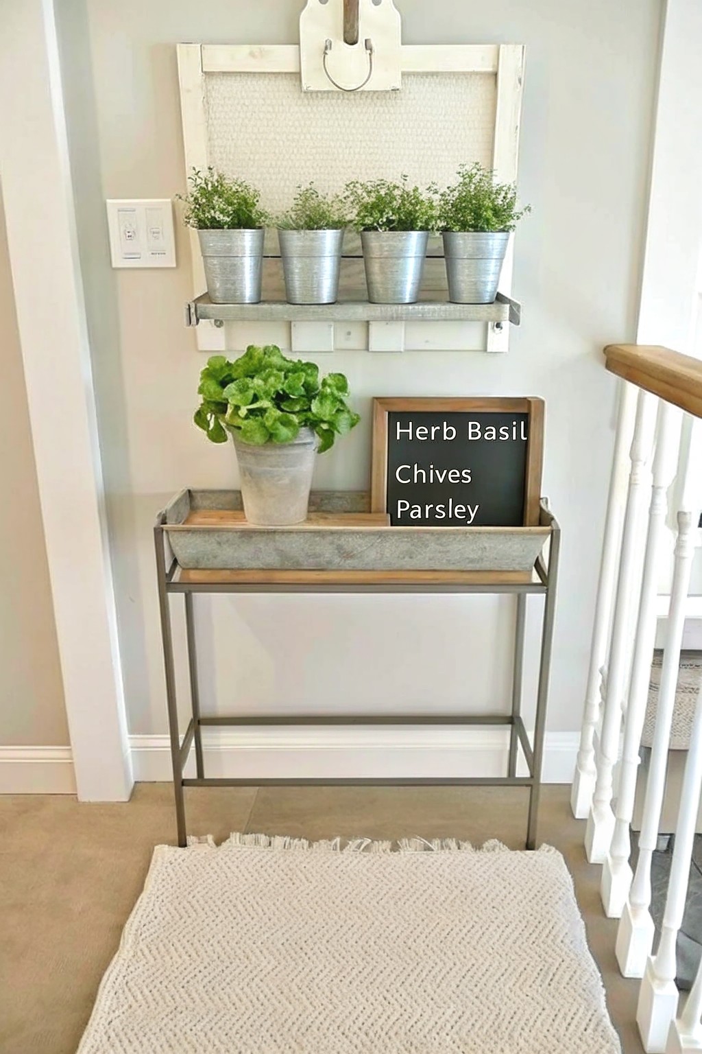 A narrow console table holds a metal tray with several potted herbs and a small chalkboard sign listing basil, chives, and parsley.