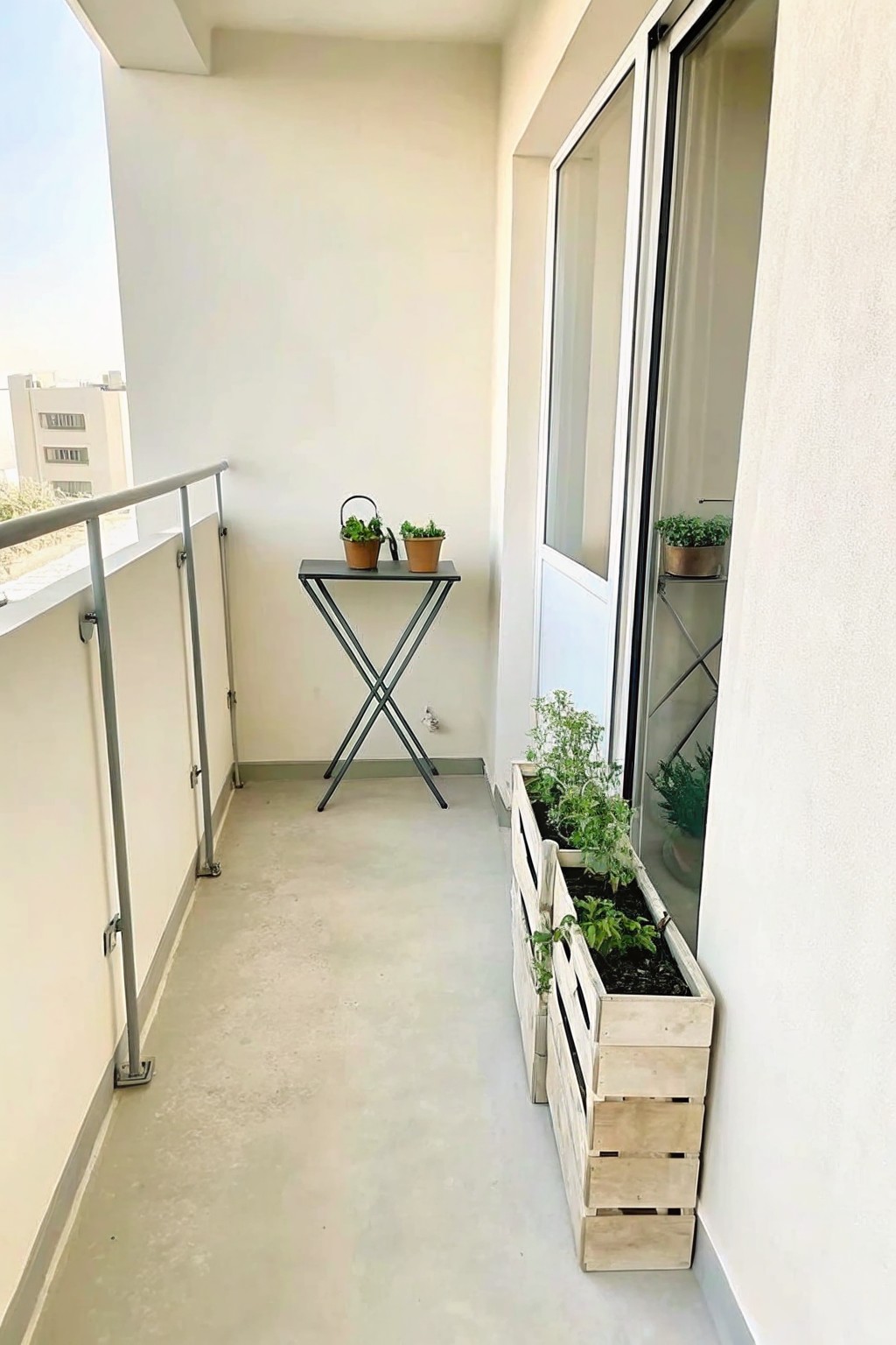 Narrow balcony with folding table, wooden planter box, potted plants, and sliding glass door.