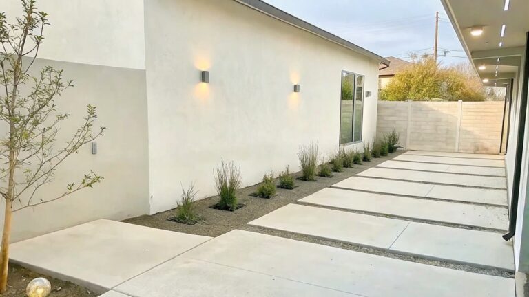 19 Smart Garden Edging Ideas That Keep Lawn Lines Crisp Modern beige house side with concrete pavers, plants, window, door, and wall lights