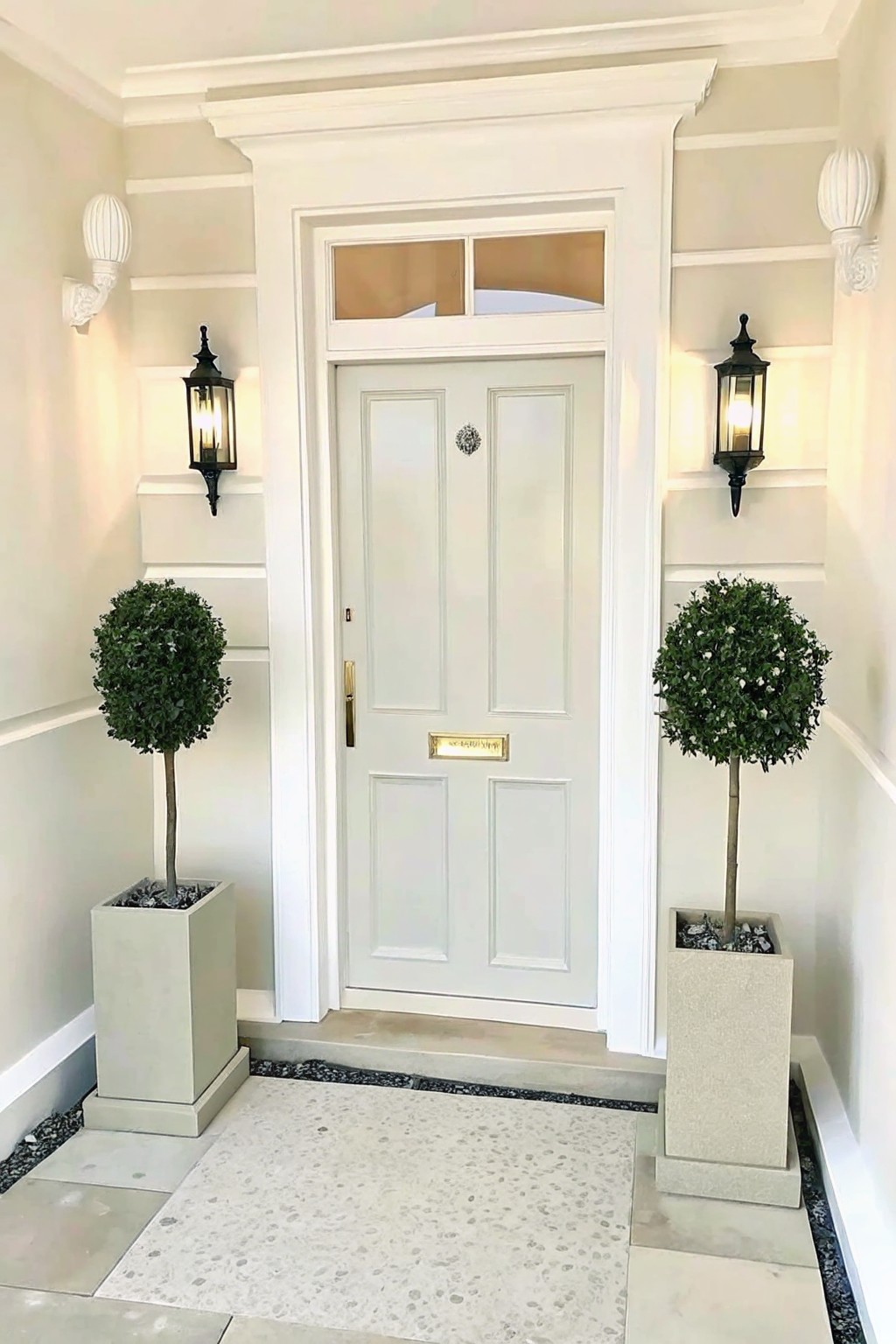 White door with topiary plants and lit black lanterns in elegant entryway