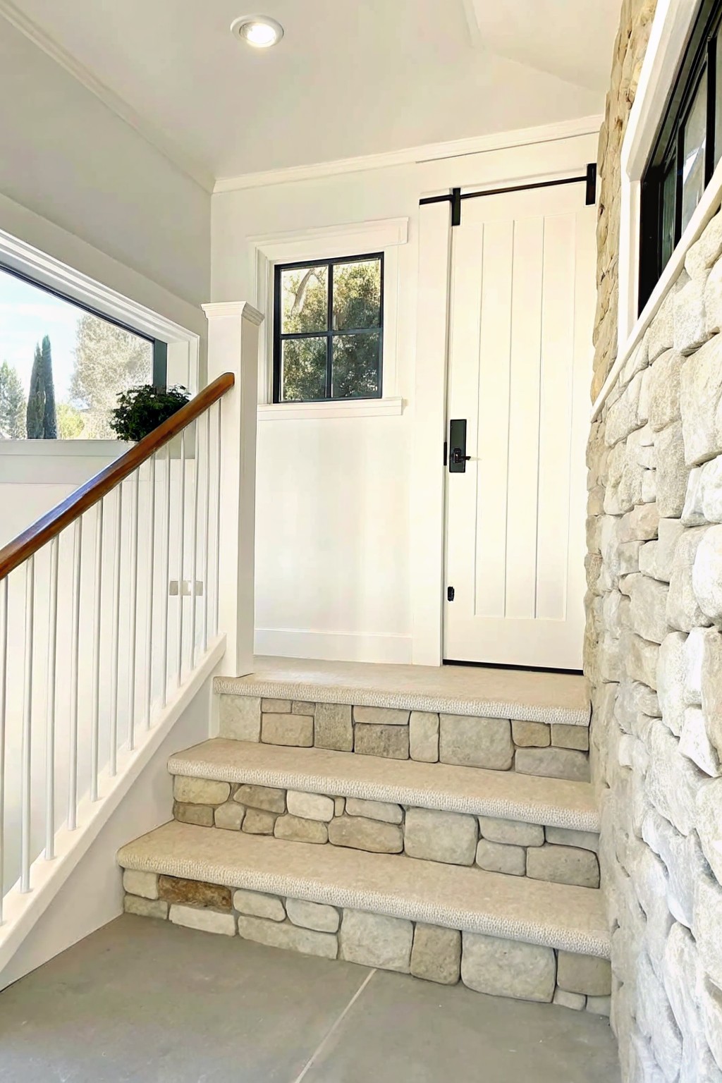 Carpeted staircase with stone sides leading to white door with black hardware.