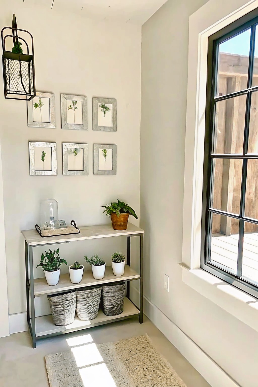 Sunlit nook with console table, potted plants, woven baskets, and framed wall art.