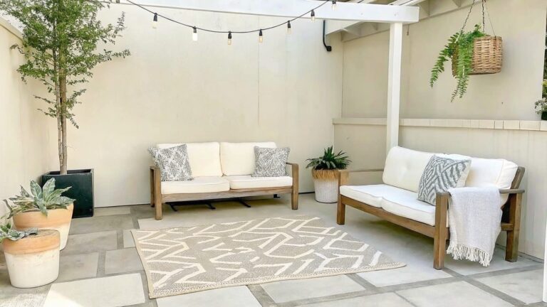 20 Unique DIY Garden Decor Ideas Using Handmade Planters and Painted Details An outdoor patio with a gray sofa, wooden coffee table, patterned rug, and several potted plants in baskets and containers on a stone floor.