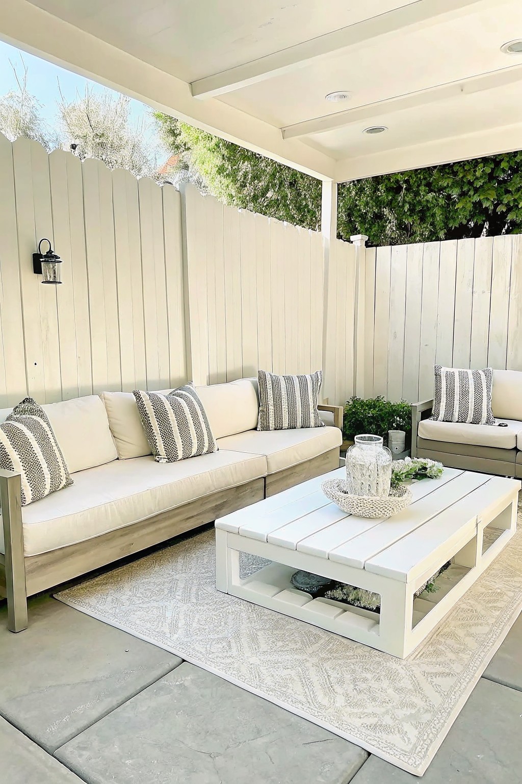 Outdoor patio with white sofa, striped pillows, coffee table on patterned rug