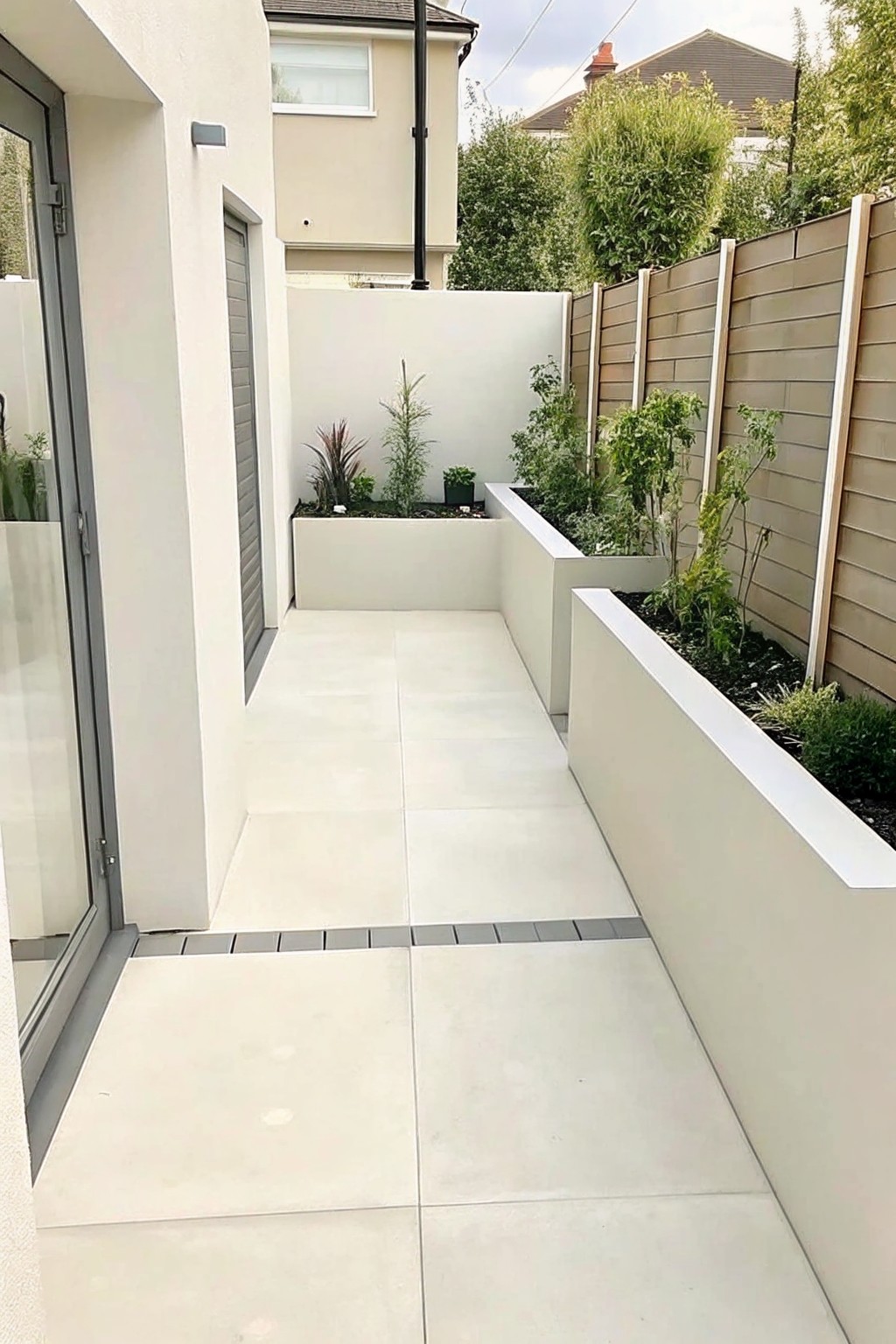 Modern white-tiled courtyard walkway with built-in planters and wooden fence
