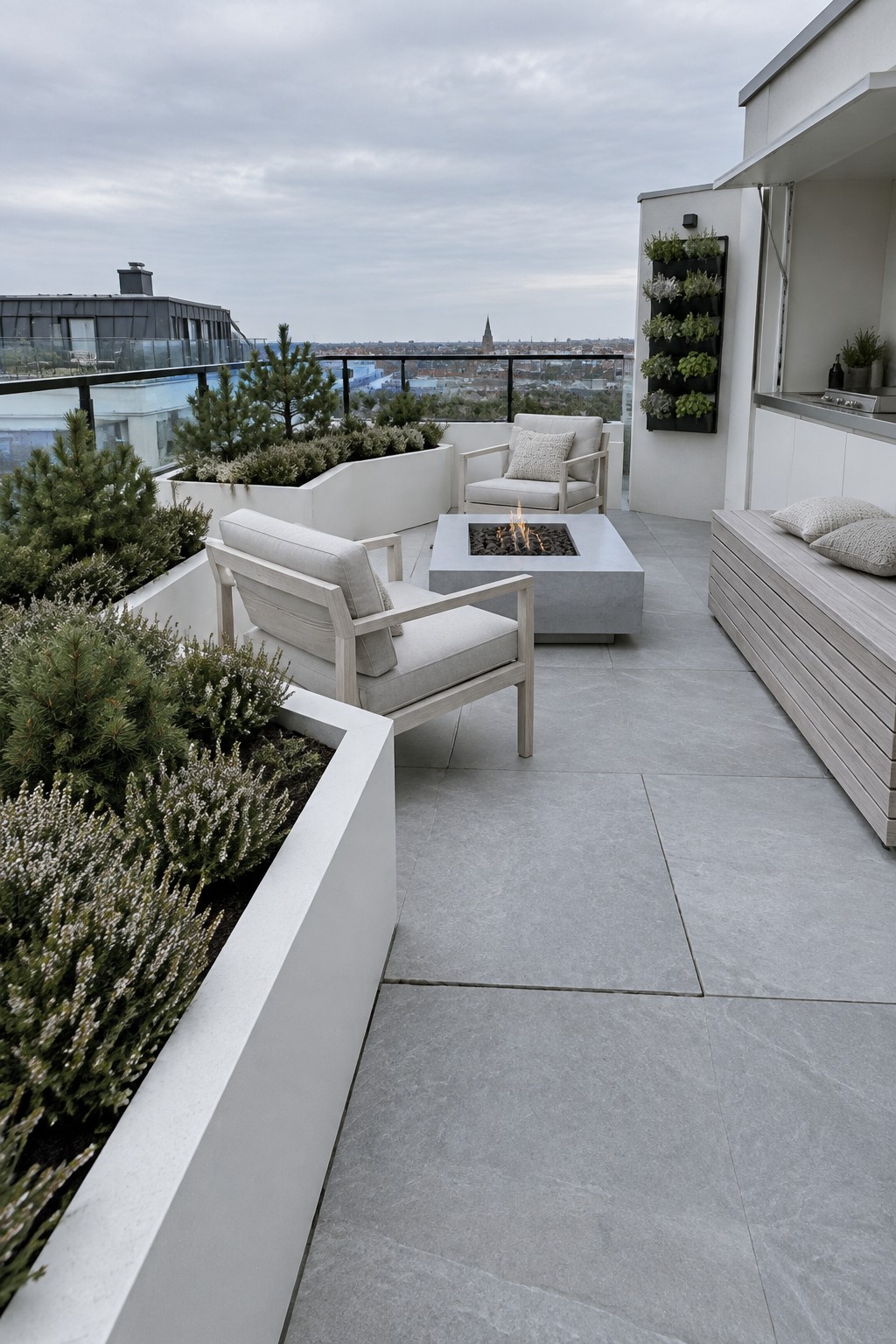 Rooftop terrace with white built-in planters holding shrubs and flowers, light wood armchairs around a square concrete fire pit, and a slatted bench along the right wall.