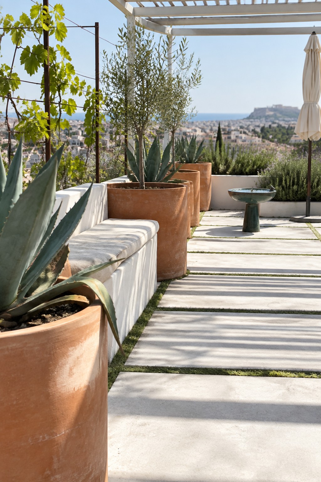 Rooftop terrace with terracotta planters, agave plants, white bench, and city sea view
