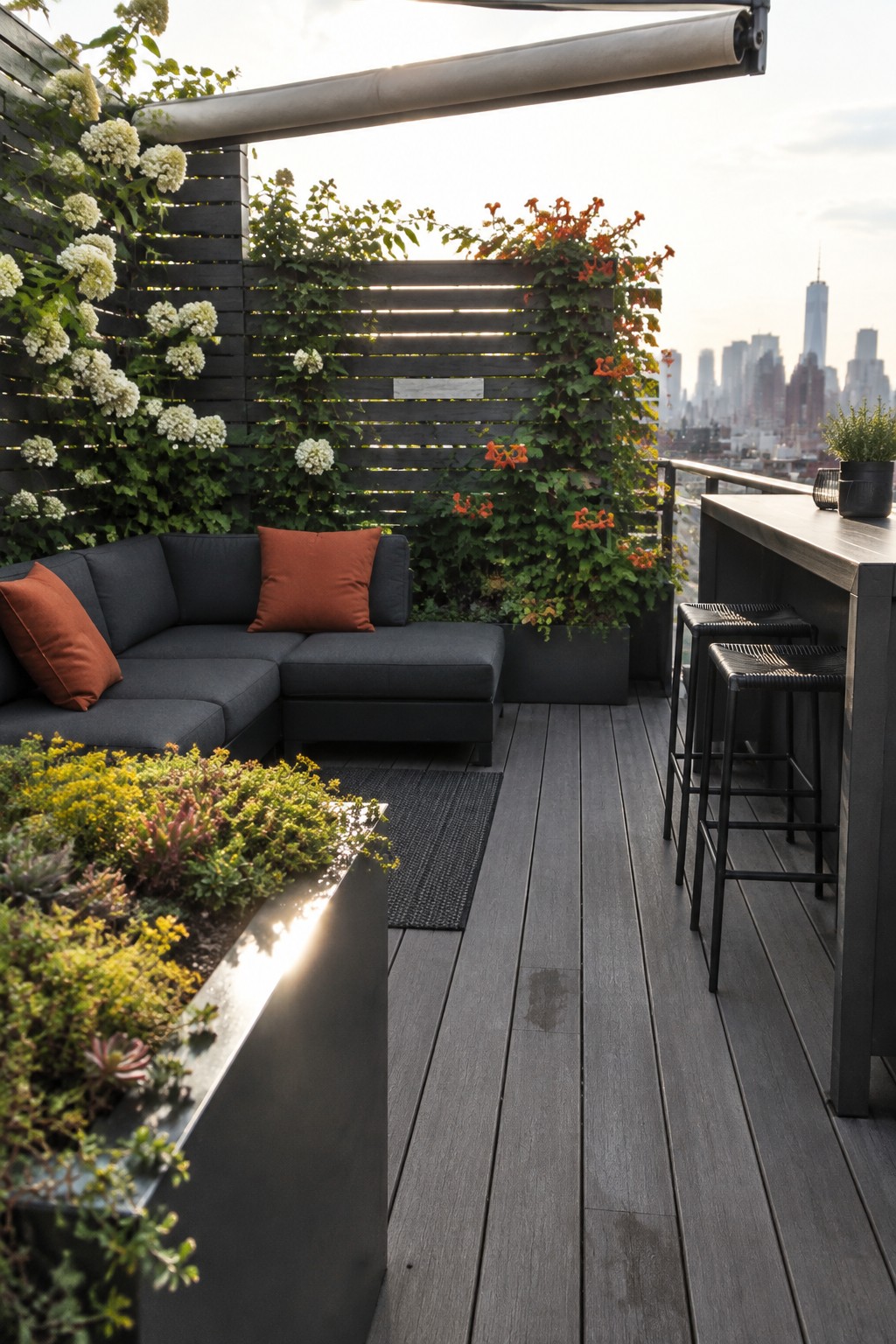 Modern rooftop deck with dark sectional sofa, orange pillows, bar stools and city skyline.