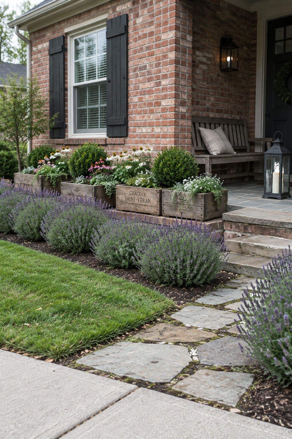 Brick house exterior with wooden crate planters holding flowers and shrubs along the foundation, lavender lining a stone path in the foreground.