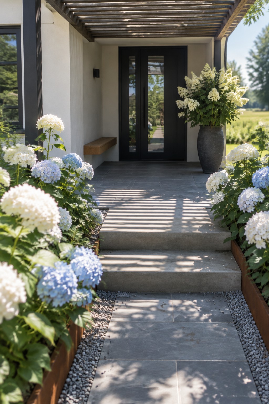White and blue hydrangeas line a stone walkway leading up steps to a covered porch with a dark front door.