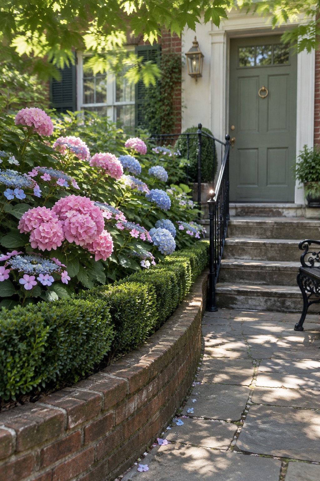Pink and blue hydrangeas grow along a brick-edged path leading to stone steps and a green front door.