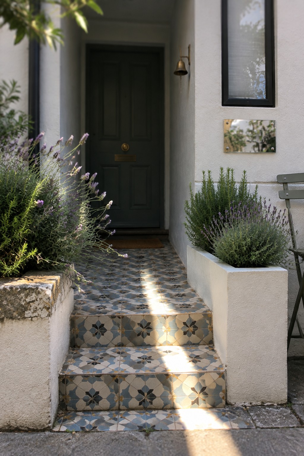 A tiled entry stairway leads to a dark front door, with lavender and other plants growing in raised beds on either side.