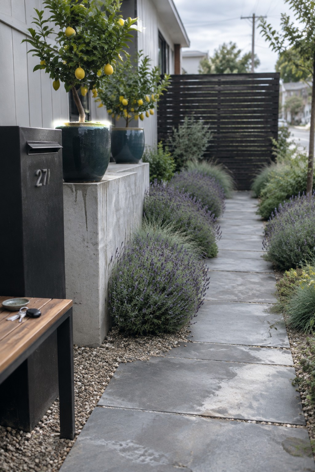 Large gray stone slabs form a front walkway bordered by lavender and lead toward a dark slatted gate.