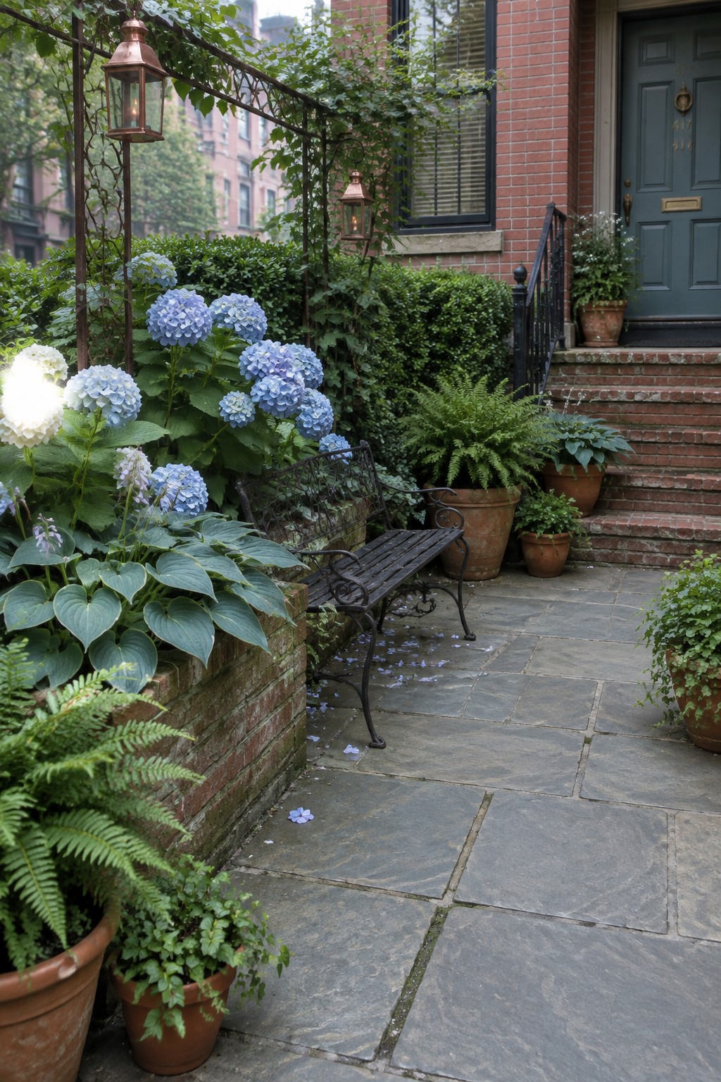 Blue and white hydrangeas and hostas grow beside a stone walkway leading to a brick townhouse entrance.